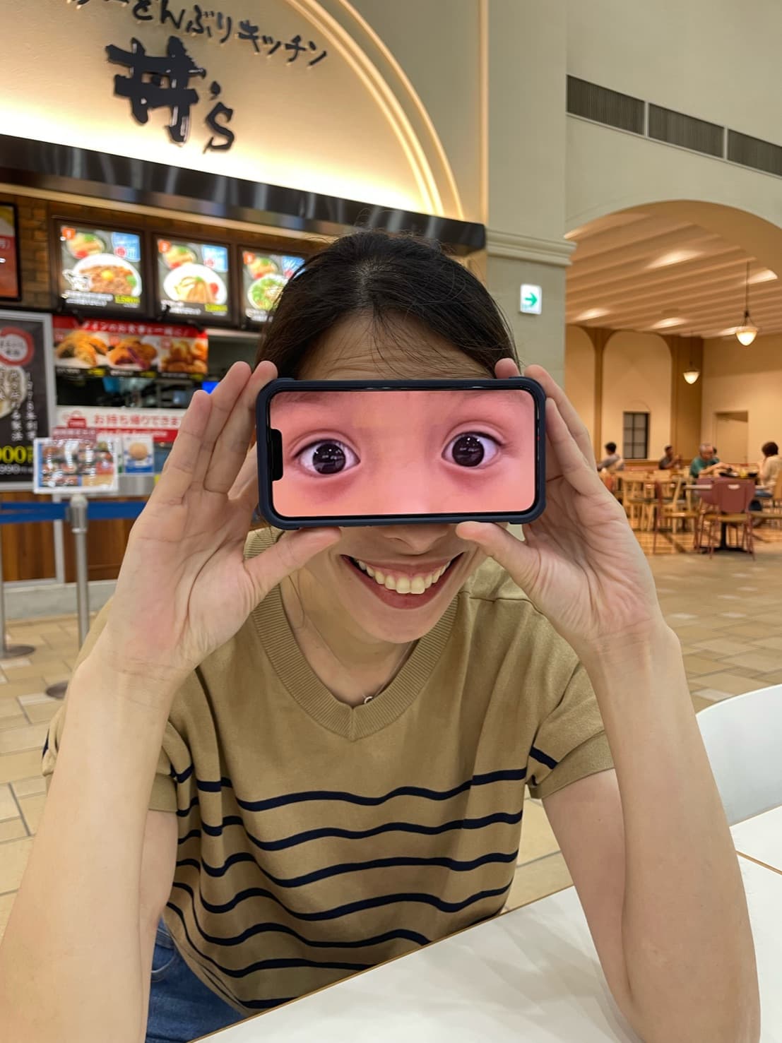 Dr. Mari holding a phone in front of her face, showing a photo of her own eyes enlarged on the screen